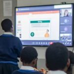 School pupil stood up looking at teaching screen